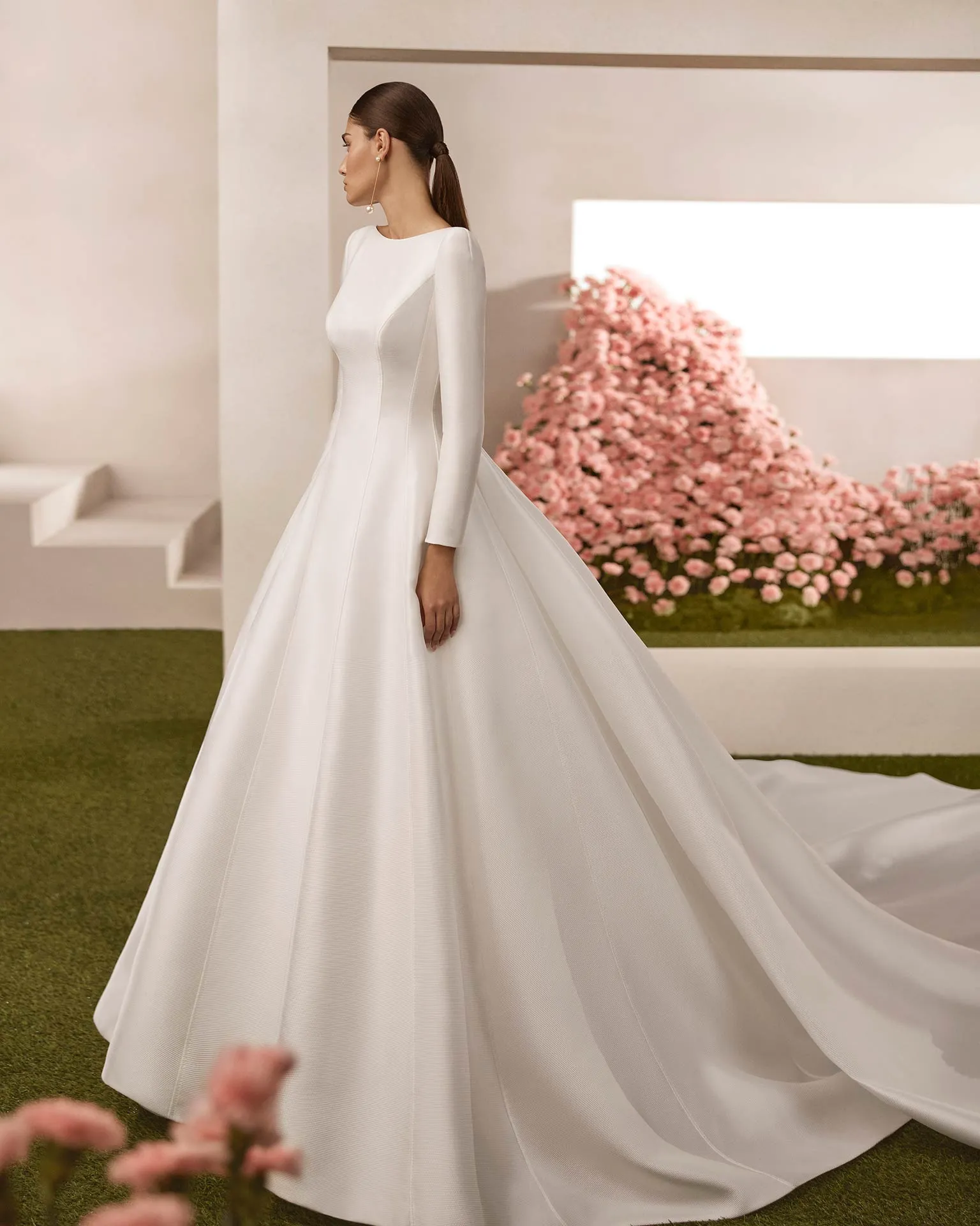Rosa Clará kapalı yaka, uzun kollu, yapısal hatlara sahip minimalist A-kesim saten gelinlik.