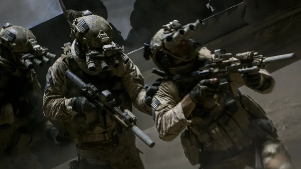 Zero Dark Thirty filminden gece operasyonu sahnesi: Gece görüş gözlükleri takmış, tam donanımlı özel birlik askerleri, bir helikopterden hızlıca inerek çatışma pozisyonu alıyor. Ortam karanlık ve yoğun toz içinde, sahne yüksek gerilimli bir askeri görevin parçası olarak sunuluyor.