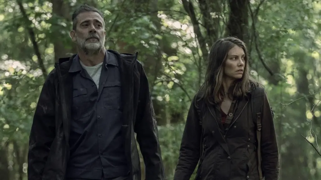 Yabancı diziler seçkisinde yer alan The Walking Dead dizisinden ormanda geçen karanlık bir sahnede Negan ve Maggie karakterleri gergin bir atmosferde yürüyor.
