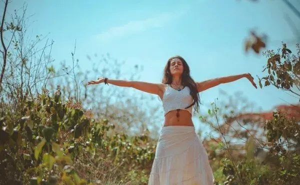 Doğanın içinde kollarını iki yana açarak özgürce nefes alan kadın; bütünsel sağlık, mindful yaşam ve doğayla uyumlu bir hayat tarzı ifadesi.