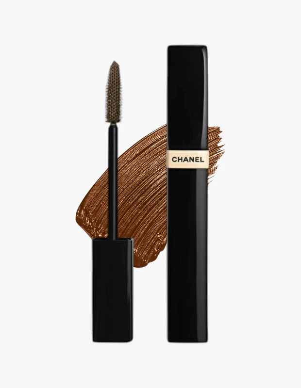 Siyah bir Chanel Les Beiges maskara tüpü, markanın adının yazılı olduğu bej bir etiketle birlikte, ürünün 10 Altın Kahve tonundaki fırçalanmış zengin bir swatch'ının önünde duran aplikatör fırçasıyla gösteriliyor.