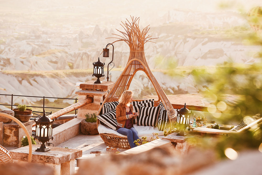 Hotel Rox Cappadocia’nın Göreme ve Güvercinlik Vadisi manzaralı terasında kahve keyfi yapan misafir