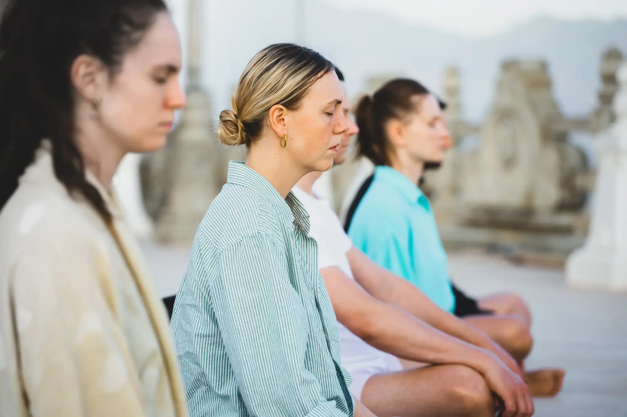 İstanbul'un dinamik atmosferinde ruhunu dinlendirmek isteyenler için ideal olan bu görüntüde, açık havada bir yoga seansında gözleri kapalı, huzurlu bir şekilde meditasyon ve nefes çalışmaları yapan birkaç kadın, zihinsel ve bedensel denge arayışını yansıtıyor.