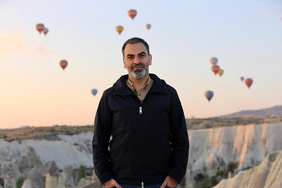 Kapadokya’da sıcak hava balonları manzarası eşliğinde peri bacalarının önünde poz veren Kayakapı Premium Caves Yönetim Kurulu Başkanı Yakup Dinler