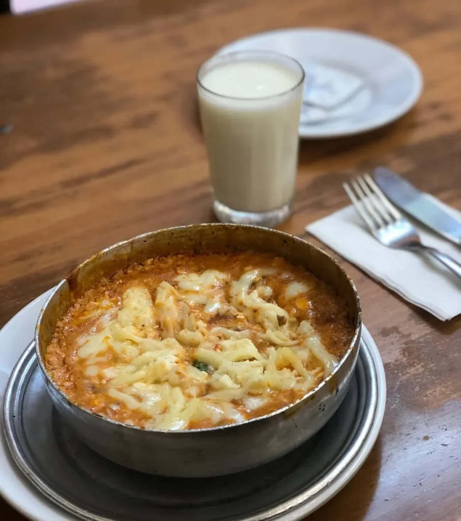 Beyoğlu Lades’te servis edilen kaşarlı menemen ve yanında taze ayran, kahvaltı ve gün ortası için popüler bir seçenek
