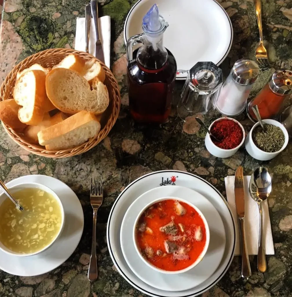 İstanbul Lale İşkembecisi’nde servis edilen kırmızı yağlı damar tuzlama çorbası; yanında ekmek, sirke, pul biber ve nane ile birlikte.