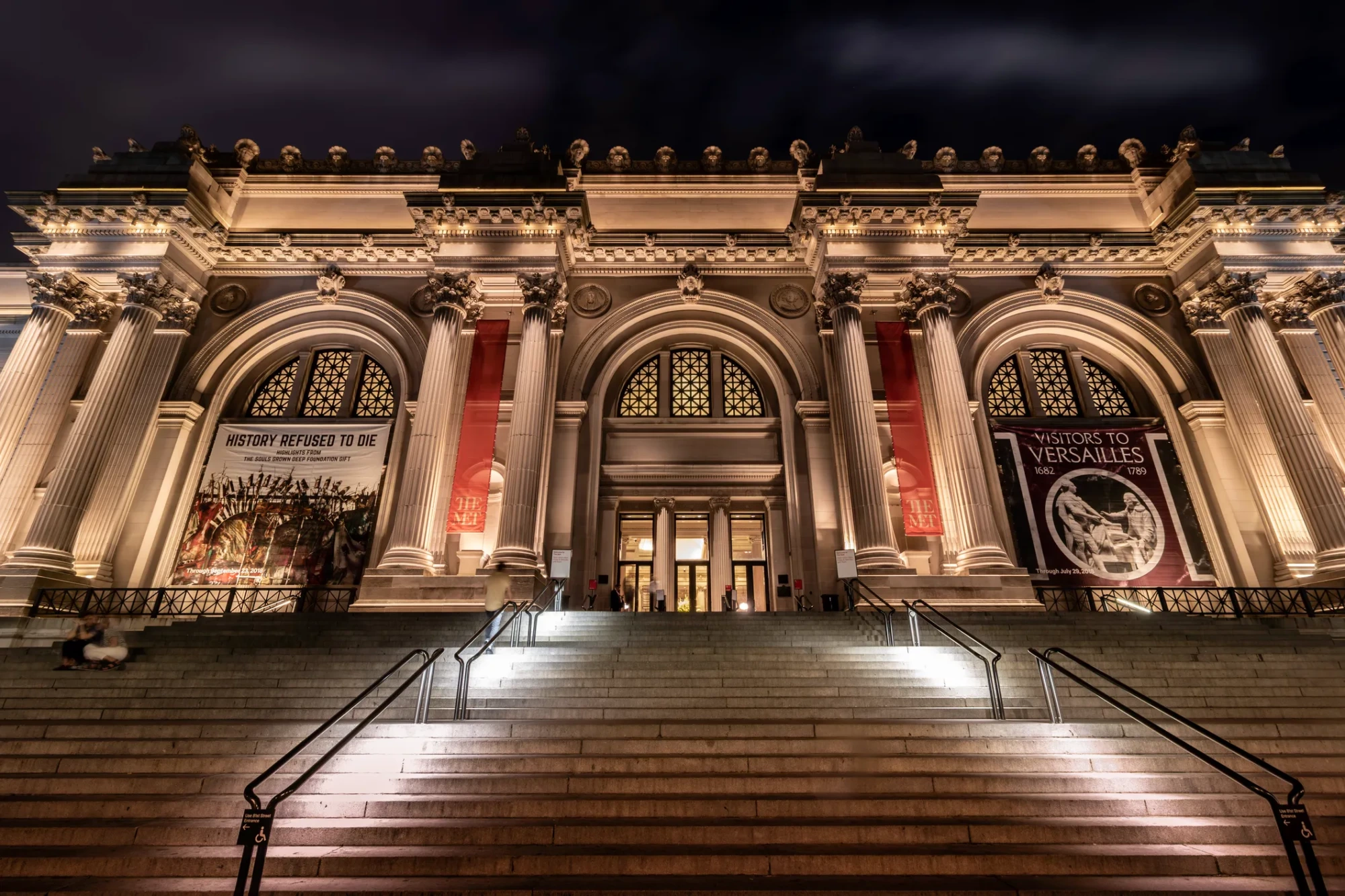 Aydınlatılmış devasa sütunları, kemerli girişleri ve uzun merdivenleriyle New York'taki Metropolitan Sanat Müzesi'nin gece çekimi, her yıl düzenlenen prestijli Met Gala etkinliğine ev sahipliği yapan tarihi ve görkemli binanın ihtişamını yansıtıyor.