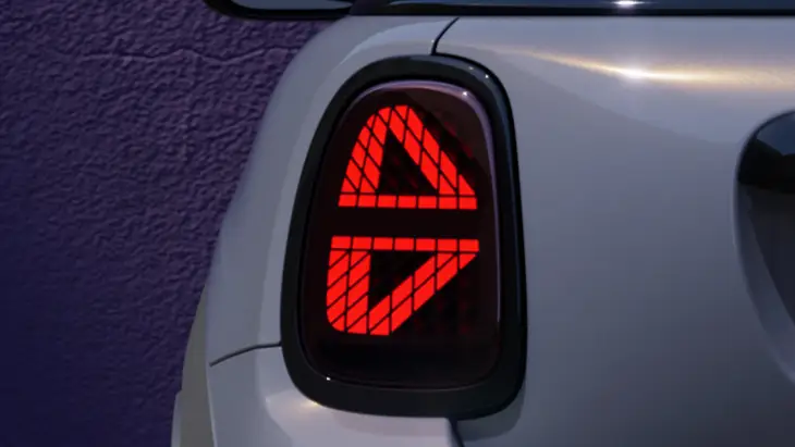 Gri Yeni MINI Cooper Cabrio'nun arka sağ kısmında yer alan, Union Jack bayrağı desenini andıran çarpıcı kırmızı LED stop lambası, aracın modern tasarımını ve dinamik, özgür ruhunu yansıtan belirgin bir detay olarak öne çıkıyor.