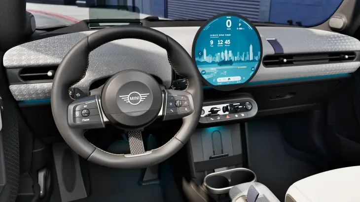 Yeni MINI Cooper Cabrio'nun iç mekanında, sürücü odaklı minimalist tasarımla çevrili direksiyonun hemen yanında yer alan, şehir silüeti ve Üstü Açık Zamanlayıcı bilgisini gösteren büyük dairesel OLED ekran, dokulu ön panel ve mavi ambiyans aydınlatması modern ve özgür bir sürüş deneyimi vaat ediyor.