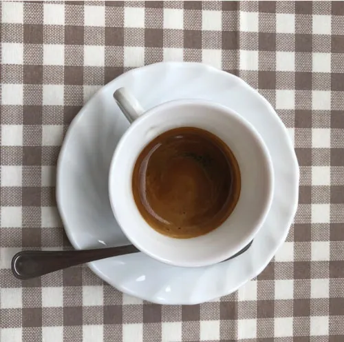 Beyaz fincanda servis edilen ristretto shot, tabağı ve kaşığıyla üstten görünüm