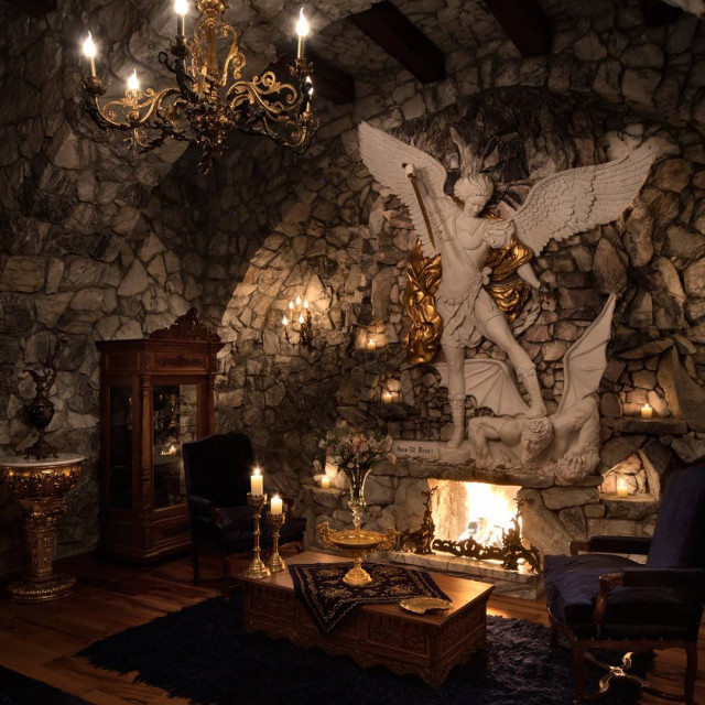 Sacred House otelde taş duvarlı, şömineli ve büyük heykelle süslenmiş şık dinlenme alanı