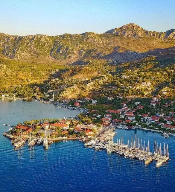 Masmavi berrak sularla çevrili Selimiye koyunun dağlık bir arka planla birleştiği geniş açılı havadan çekilmiş bu görüntüde, sahile yayılmış ve denize uzanan bir yarımadada kırmızı çatılı evler, yemyeşil ağaçlar ve marinalara demirlemiş çok sayıda yelkenli ile yatlar göz alıcı bir şekilde yer alıyor.