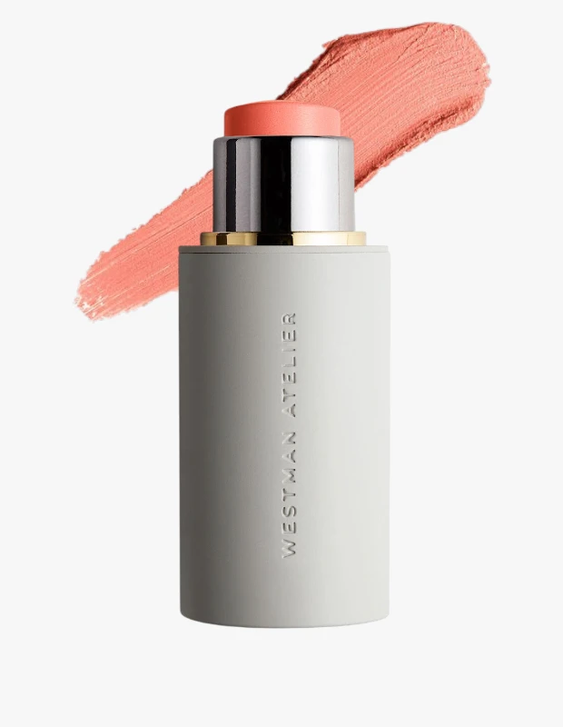 Beyaz bir arka plan üzerinde, metalik gümüş ve altın detaylara sahip açık gri WESTMAN ATELIER Baby Cheeks allık stick Minette rengi görülüyor; ürünün şeftali tonlu turuncu renginden bir sürüm de arka planda yer alıyor.