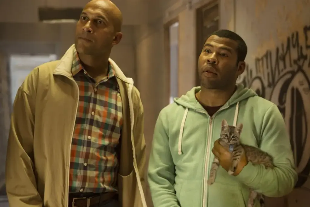 Keanu filminden bir sahnede, oyuncular Jordan Peele sevimli tekir yavru kedi Keanu'yu kucağında tutarken, Keegan-Michael Key ile birlikte harap bir koridorda dikkatle etrafa bakınıyor; bu görüntü, kayıp bir kedinin peşine düşen iki adamın macerasını anlatan ve kedi severlerin favorisi olacak kedili filmler arasından bu aksiyon komedi filmini mükemmel yansıtıyor.