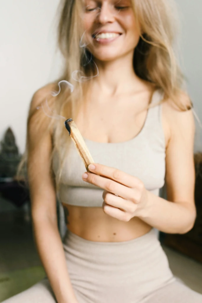 Palo santo tütsüsü yakan, gülümseyerek meditasyona hazırlanan kadın.