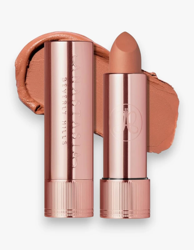 Beyaz bir zeminde, parlak gül altın rengi ambalajlı Anastasia Beverly Hills marka bir adet kapalı ve bir adet ucu açık vizon rengi mat ruj, arkasında ise bu mat rujun pürüzsüz dokulu bir swatch örneği gösteriliyor.