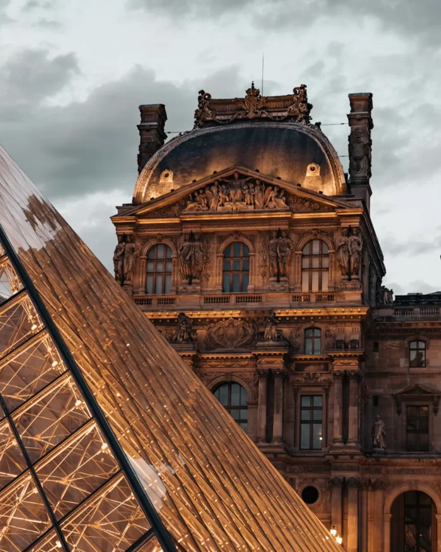 Louvre Müzesi'nin akşamüstü ışıklarıyla aydınlanan cam piramidi ve tarihi binası, Babalar Günü tatil önerileri içinde müze ve sanat rotası arayanlar için etkileyici bir Avrupa müzesi atmosferi sunuyor.