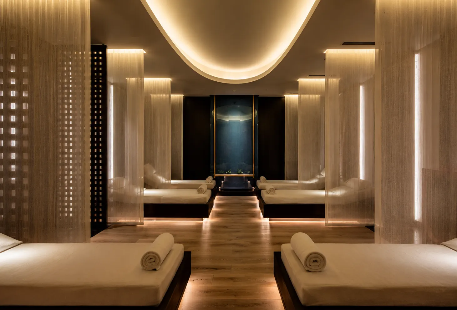 Hilton Bomonti Spa'nın huzurlu dinlenme alanında, yanlarda sıralanmış beyaz nevresimli rahat yataklar, tavan ve zeminden yayılan yumuşak dolaylı ışıklarla aydınlatılmış şeffaf perdelerle ayrılmış bir şekilde dingin bir atmosfer sunuyor.