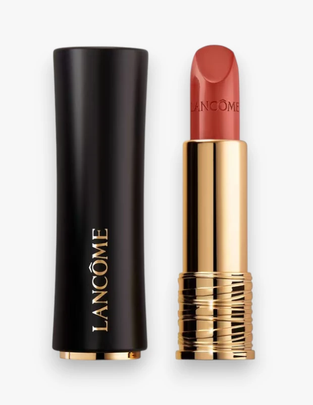 Siyah zarif kapağı yanında duran altın renkli Lancôme L'Absolu Rouge ruj, kapağındaki dikey Lancôme yazısı, parlak altın gövdesi ve belirgin mercan tonlarında dudak boyasıyla ürünün detaylarını yakından sergiliyor.
