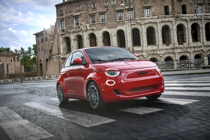 Tarihi kemerli taş binaların önünden geçen yaya geçidinde, farlarındaki modern yuvarlak LED ışıkları belirgin, kırmızı renkteki Fiat 500 elektrikli otomobil, şehir içi kullanım için ideal seçeneklerden birini sunuyor.
