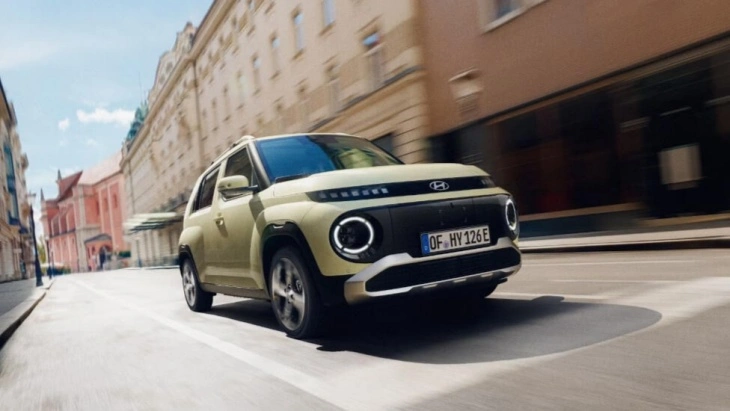 Şehir sokaklarında seyir halinde açık yeşil Hyundai Inster elektrikli mini SUV.