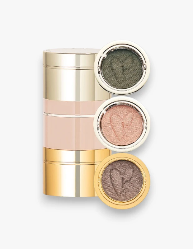 Westman Atelier Eye Pods Rendez-Vous göz farı paletinin üç ayrı renk kapsülü, koyu yeşil, şeftali ve kahverengi-gri tonlarında olup her birinde kalp şeklinde bir kabartma bulunuyor ve altın rengi ile soluk pembe lüks ambalajları ile birlikte beyaz bir zeminde şık bir şekilde sergileniyor.