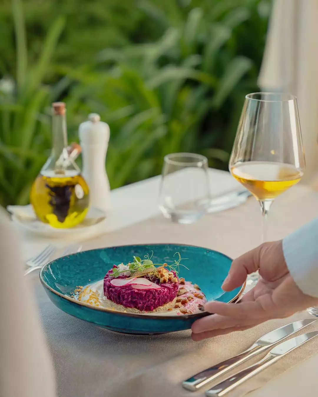 Karadağ'ın Adriyatik kıyılarındaki seçkin restoranlarından Rosemarine'de, bir garsonun özenle masaya bıraktığı, pancar tabanlı canlı mor renkli tartarın beyaz sos, taze filizler ve turp dilimiyle zenginleşen şık sunumu, füzyon mutfağının sunduğu Akdeniz lezzetlerini vurguluyor.