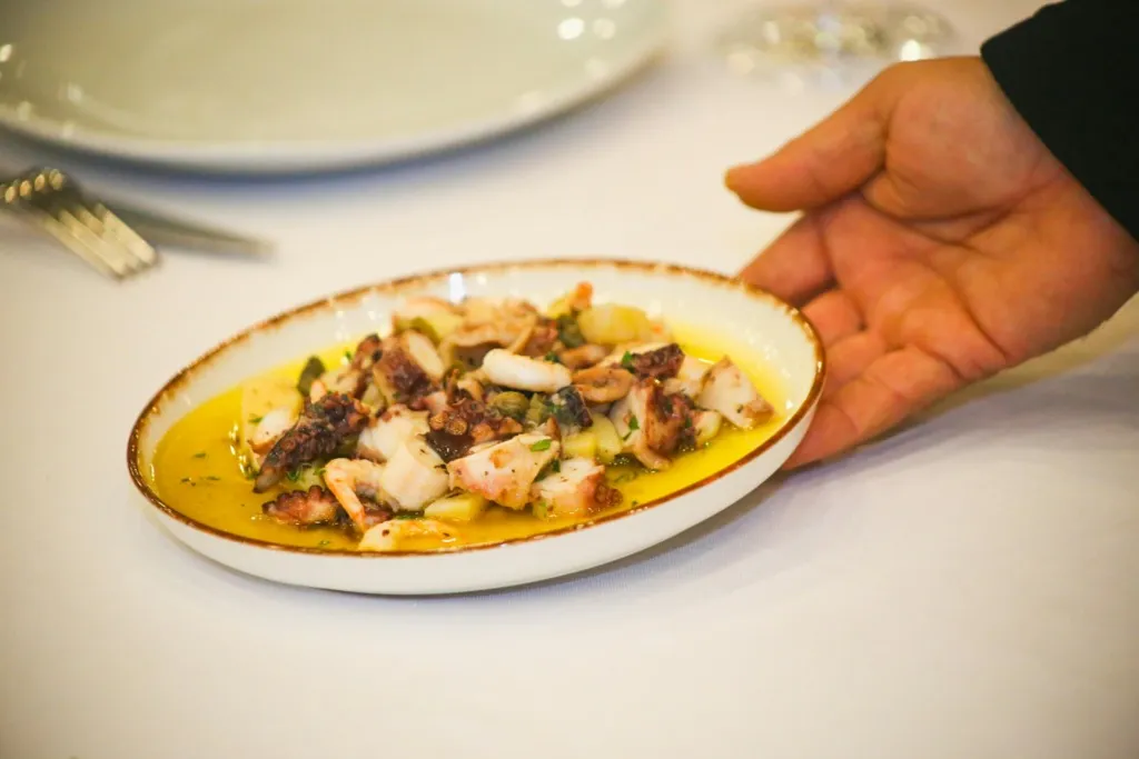 Zeytinyağı ve baharatlarla hazırlanmış ahtapot salatası, servis edilmek üzere masaya konuluyor.