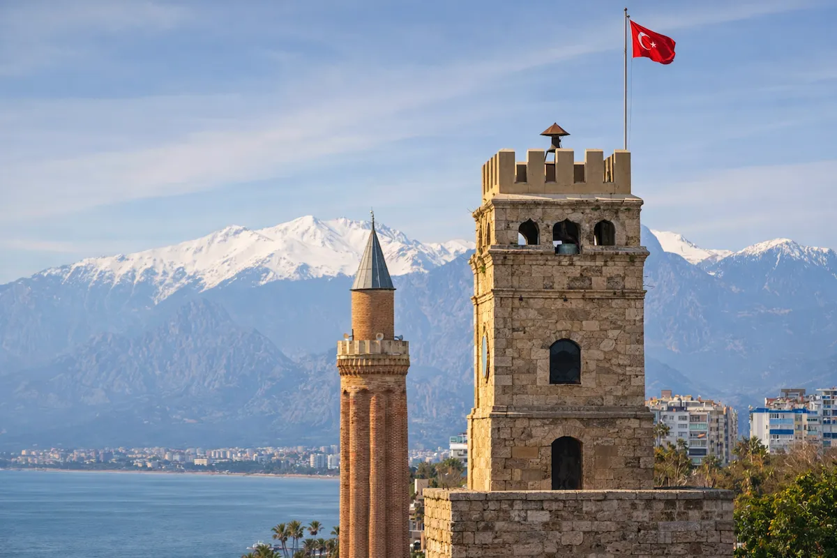 Antalya'nın önemli sembollerinden taş duvarlı Saat Kulesi'nin üzerinde dalgalanan Türk bayrağı ve hemen yanında yükselen yivli tuğla Yivli Minare, karlı dağların ve Akdeniz'in masmavi sularının oluşturduğu büyüleyici manzarayla çevrili.