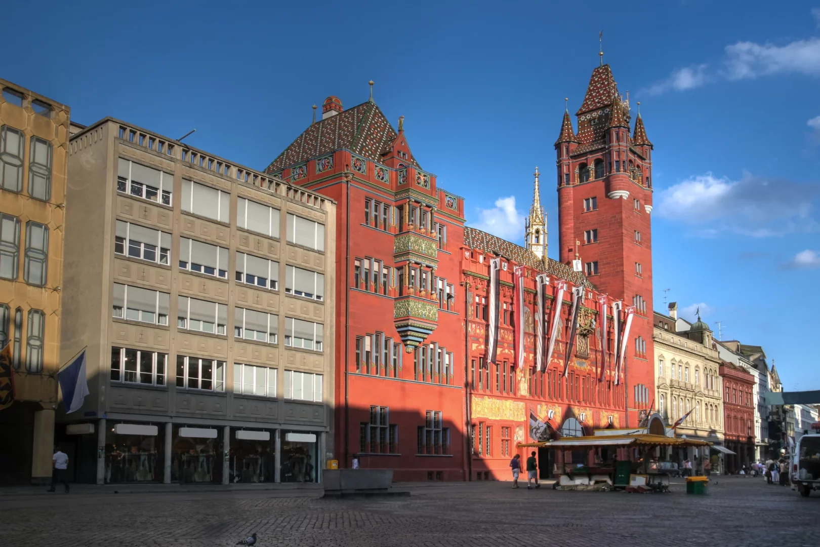 Basel gezilecek yerler arasında yer alan Marktplatz ve kırmızı cephesiyle dikkat çeken Rathaus, güneşli bir günde görüntüleniyor.