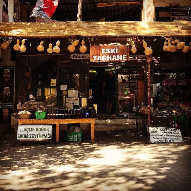 Bayır Köyü Marmaris'te, doğal ürünler ve özellikle soğuk sıkım zeytinyağı satan, önünde kuru kabaklar asılı, üzerinde Eski Yağhane tabelası olan geleneksel bir dükkanın dış cephesi görünüyor.