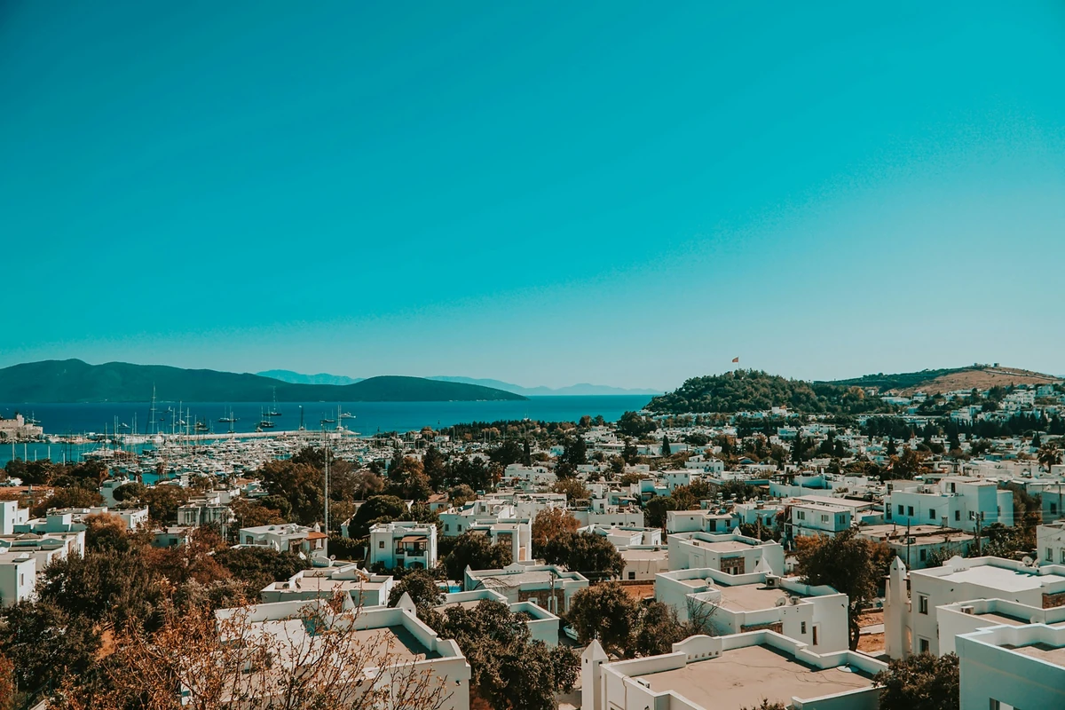 Bodrum'da yaşamak için şehir, marina, beyaz evler, yeşil tepeler ve masmavi denizi bir arada gösteren geniş Bodrum panoraması.