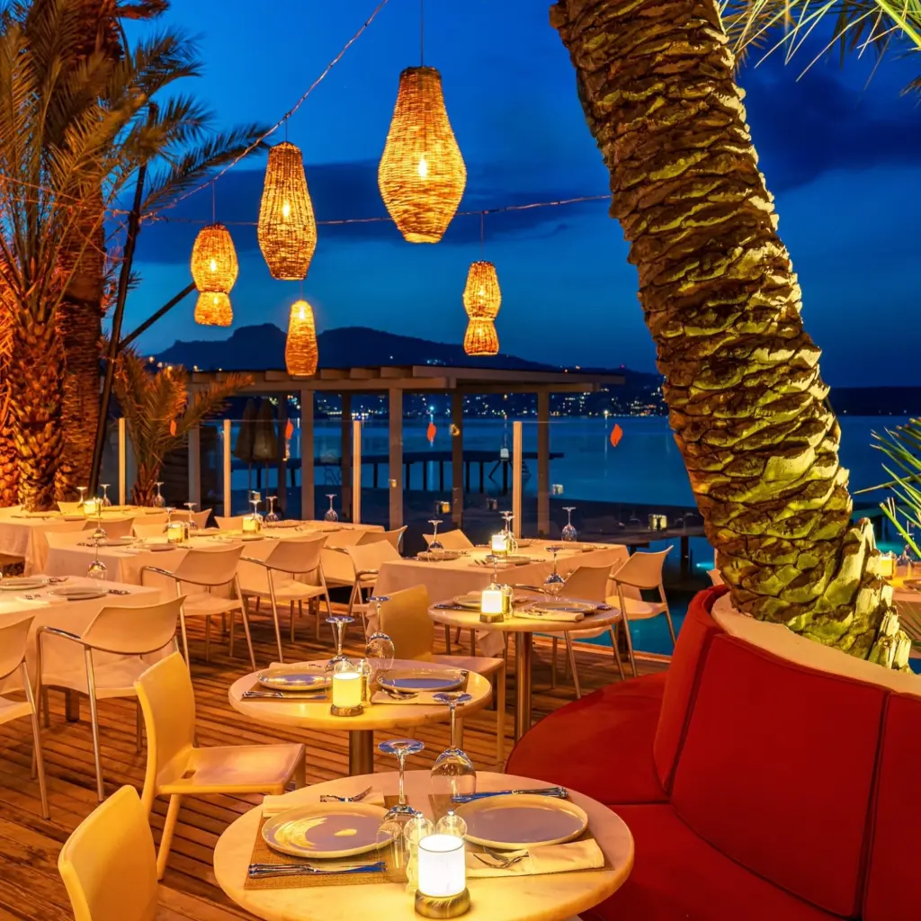 Bodrum'un eşsiz sahilinde yer alan, hasır avizelerden yayılan sıcak ışıklarla aydınlatılmış, şık masaları ve denize nazır huzurlu atmosferiyle dikkat çeken bu restoran, misafirlerine unutulmaz bir akşam yemeği deneyimi sunuyor.
