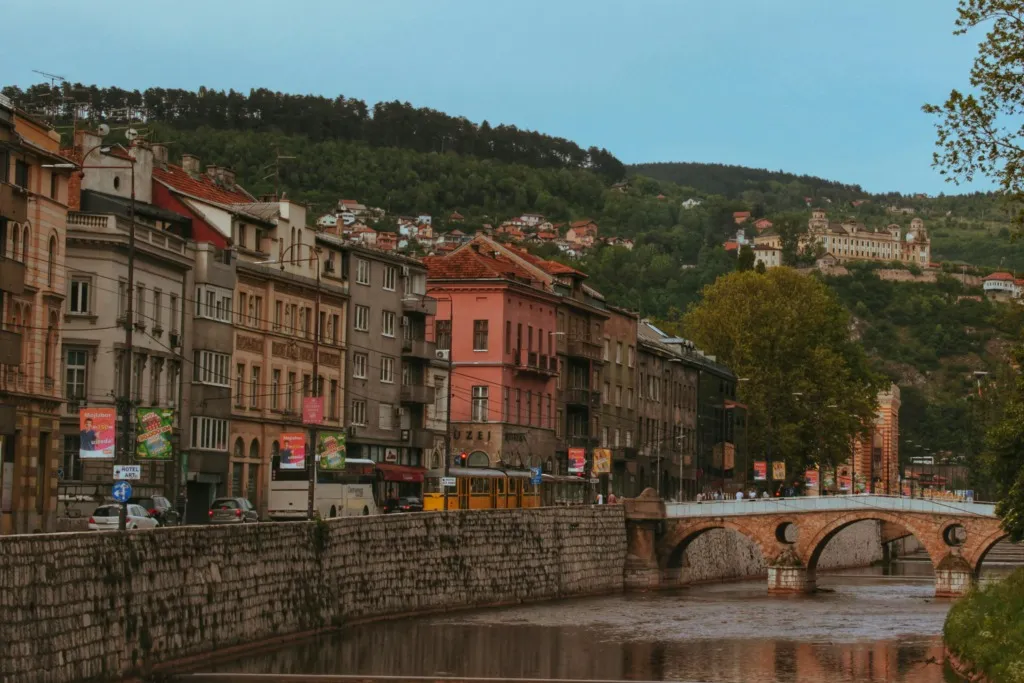 Bosna-Hersek Saraybosna şehir manzarası – Miljacka Nehri üzerindeki taş köprü ve tarihi binalar, vizesiz Balkan tatil rotası