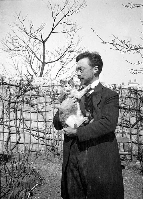 Siyah beyaz bir fotoğrafta, gözlüklü ve bıyıklı Wassily Kandinsky 1910 yılında muhtemelen bir bahçede, kollarında alacalı bir kedi tutarak hayvanla sıcak bir an paylaşıyor, arkada çıplak ağaçlar ve sarmaşıklı bir çit görünüyor.