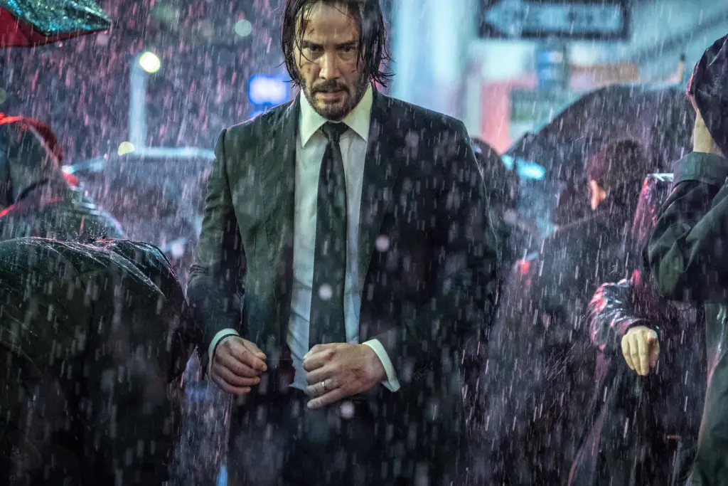 John Wick'i canlandıran Keanu Reeves, John Wick 3: Parabellum filminde, yağmur altında yürürken.