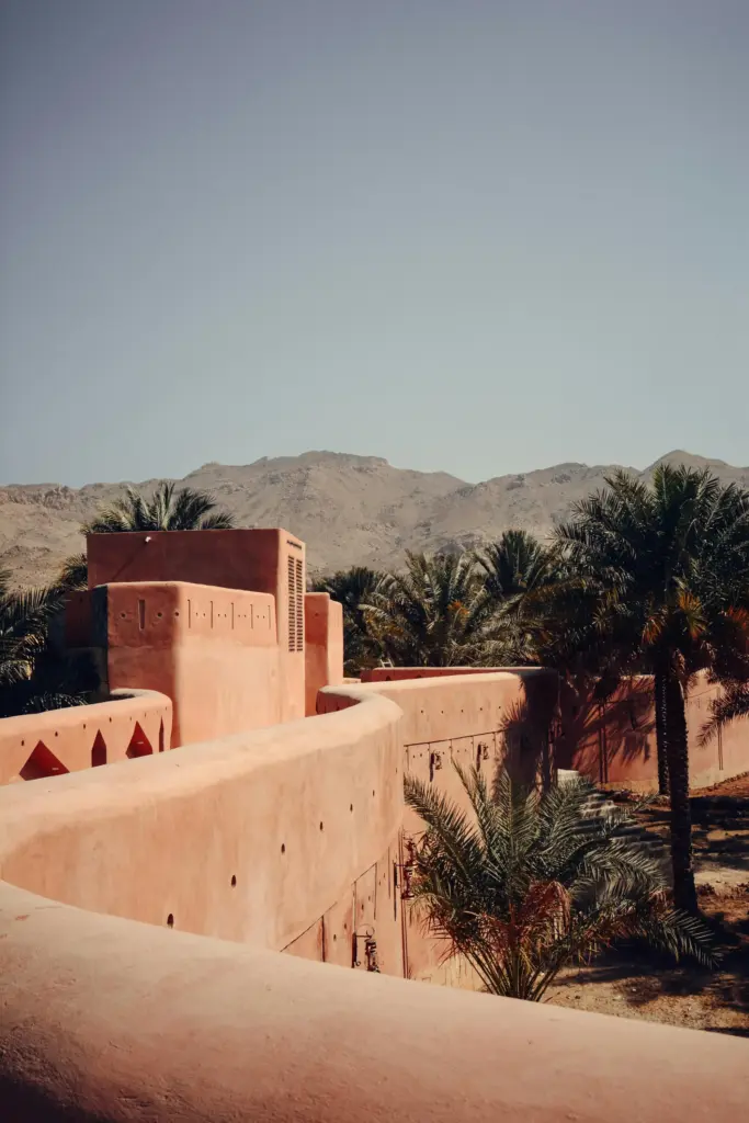 Umman’da palmiye ağaçlarıyla çevrili, dağların eteklerindeki tarihi Nizwa Kalesi’nin surları.