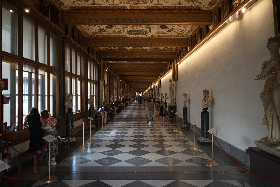 Uffizi Müzesi'nin uzun, sanat eserleriyle dolu koridorunda, siyah beyaz dama desenli zeminde yürüyen ziyaretçiler, soldaki pencerelerden gelen ışıkla aydınlanan heykellere ve tavanın süslü detaylarına hayranlıkla bakıyorlar.