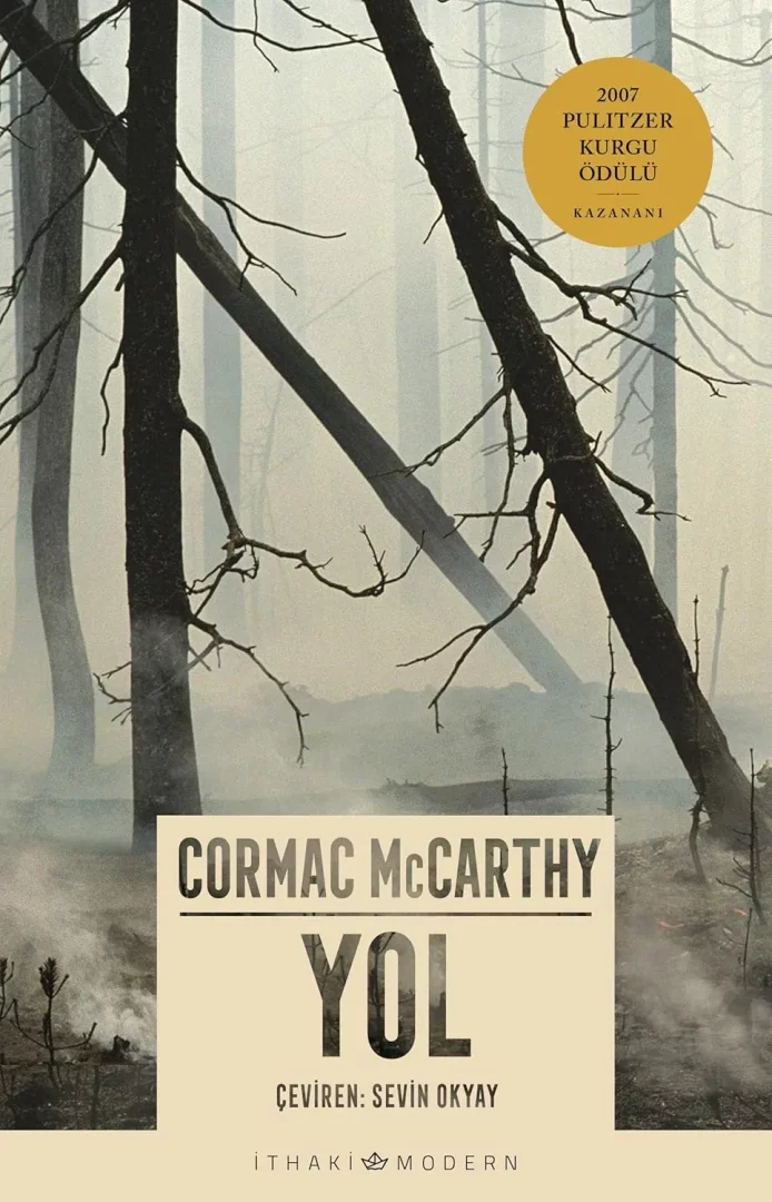Cormac McCarthy'nin YOL adlı eserinin kapağı, sisli bir vadideki çıplak ve devrilmiş ağaç gövdeleriyle, dumanlı bir orman yolunu çağrıştıran kasvetli ve ıssız bir manzarayı gözler önüne sererken, 2007 Pulitzer Kurgu Ödülü'nü kazandığı bilgisini de barındırarak, babalık yolculuğunun belirsizliklerle dolu ve bilgelik gerektiren anlarını simgeleyen derin bir kitap olarak babaların kütüphanesine eklenebilecek güçlü bir görsel sunuyor.