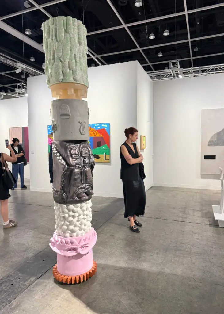 Çeşitli yüzey dokularına sahip katmanlı totem heykel, Art Basel’de kültürel motifler ve çağdaş heykel dili arasında dikkat çekici bir geçiş kuruyor.