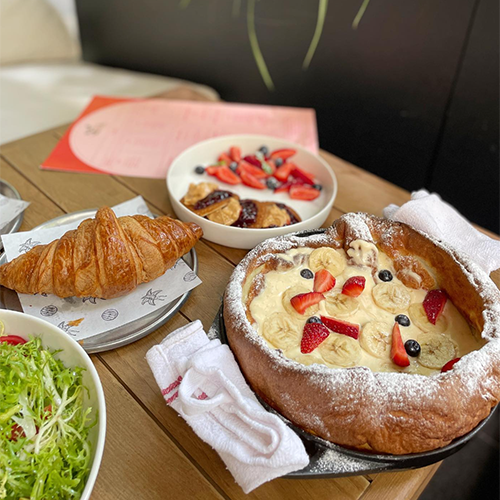 Fenerbahçe'de bulunan Cafe Fern'de masada servis edilen, pudra şekeri ve taze meyvelerle süslenmiş bir Dutch Baby (Alman pankeki). Masada ayrıca sade kruvasan, meyve dolu bir kase ve yeşillik salatası da görülüyor.