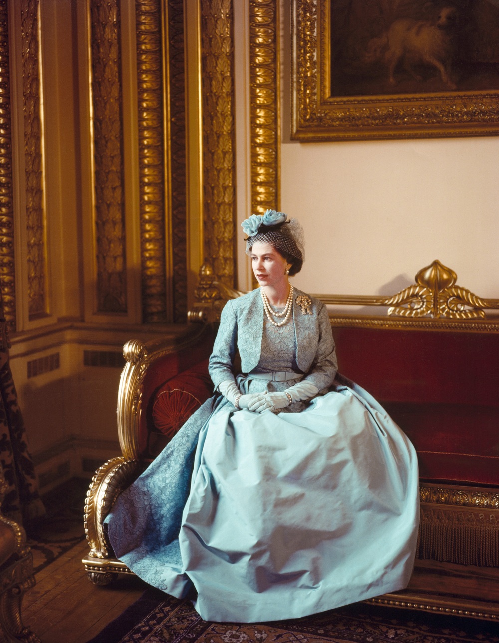 Cecil Beaton tarafından çekilmiş, Victoria and Albert Museum’da altın varaklı salonda oturan dönem kostümlü Kraliçe II. Elizabeth portresi