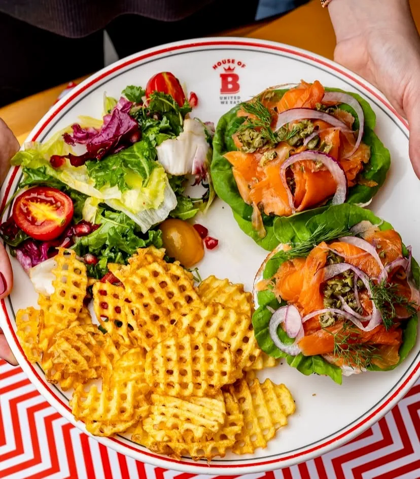 House of B restoranında servis edilen, yanında waffle patates ve yeşil salata ile birlikte marul yaprağı üzerinde somon füme tabağı.