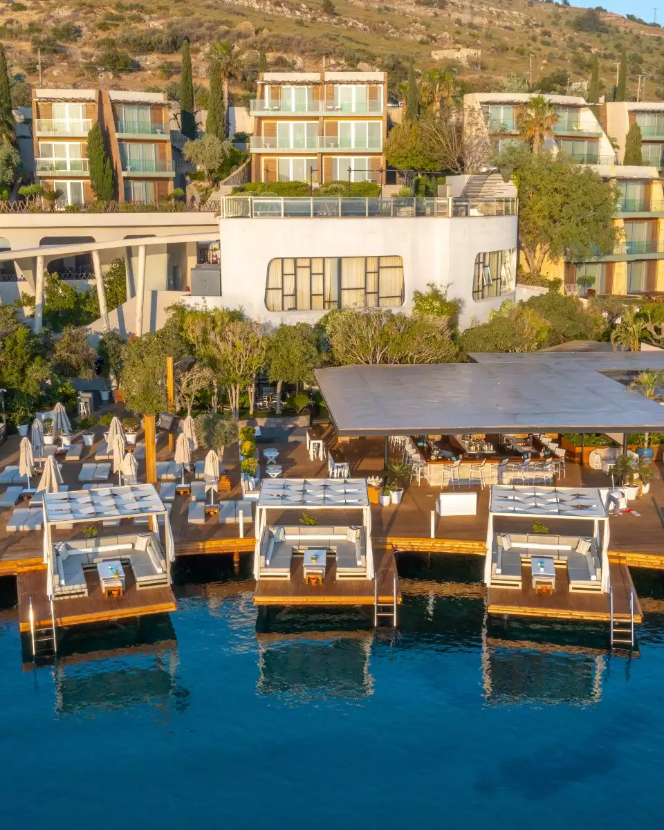 Kuum Beach Göltürkbükü’nde geniş ahşap platform, VIP cabanalar, şezlonglar ve sakin deniz manzarası