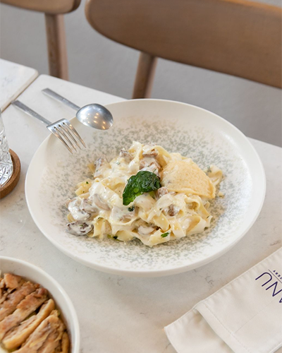 Suadiye'deki Manu Bakery & Eatery'de masada servis edilen, kremalı mantar sosu ve parmesan peyniri ile hazırlanan bir fettuccine tabağının yakın çekimi.