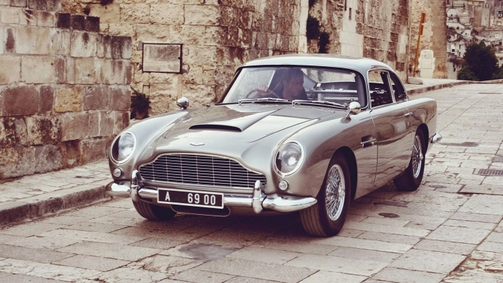 James Bond filmleriyle ünlü Aston Martin DB5, taş sokaklarda sergilenen gümüş rengi gövdesiyle klasik İngiliz otomobil zarafetini yansıtıyor.
