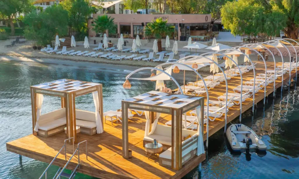 Iconic Beach Bodrum Gümbet’te ince kum plaj, ahşap iskele, şezlonglar ve berrak deniz manzarası
