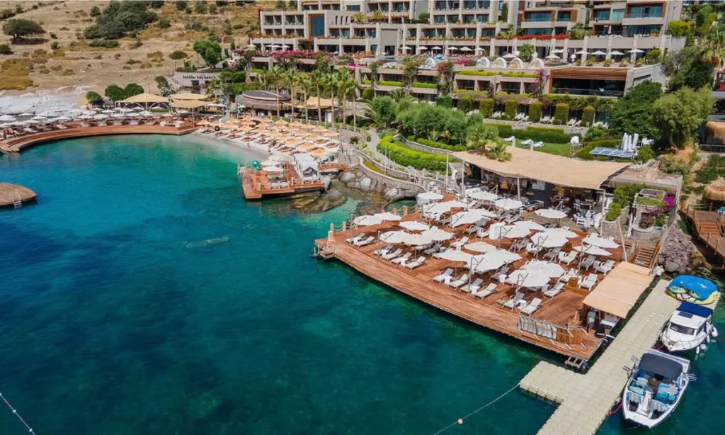 Buddha-Bar Beach Bodrum Asarlık Koyu’nda beyaz kum plaj, ahşap iskele, cabanalar ve turkuaz deniz manzarası