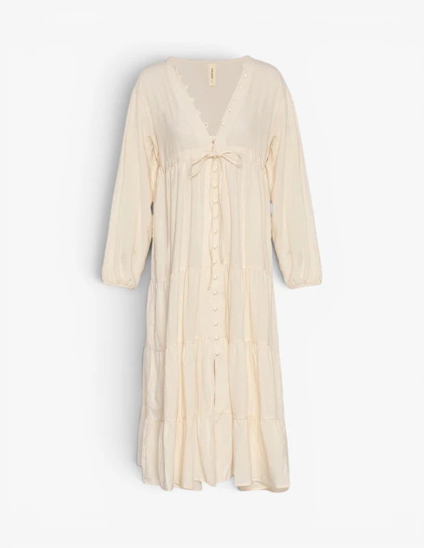 Marka Adı: Heliophilia
Ürün Adı: Heliophilia Kadın Boho Elbise
Ürün Cinsiyeti: Kadın
Ürün Tipi: Elbise
Ürün Sezonsallığı: Yaz
Ürün Çeşidi: Boho Midi Elbise
Ürün Özellikleri: Bu açık bej veya krem rengi elbise, hafif ve dökümlü dokusuyla yaz günleri için ideal bir parça. Rahat ve bohem bir silüete sahip olup V yakası, uzun kolları ve beli vurgulayan bağcıklı detaylarıyla öne çıkar. Elbisenin ön kısmında boydan boya uzanan düğmeler bulunur ve etek ucu kat kat volanlı tasarımıyla hareketli bir görünüm sunar. Midi boy kesimi sayesinde hem şık hem de konforlu bir kullanım vadederken, doğal kumaş hissiyle cilt dostudur.
Öne Çıkan Detaylar:
- V yaka tasarımı ve boydan boya düğme kapanışı
- Beli vurgulayan, ayarlanabilir bağcıklı detay
- Kat kat volanlı ve dökümlü midi etek kesimi
Kimler Kullanıyor?: Tatil bavulunda çok yönlü ve stil sahibi parçalara yer vermek isteyenler, plajdan akşam yemeğine uzanan günlerde rahatlıktan ödün vermeyenler, bohem ve doğal şıklığı sevenler bu elbiseyi tercih edebilir. Minimalist ancak etkileyici bir görünüm arayanlar, yumuşak dokular ve hafif siluetlerle kişisel stillerini yansıtmak isteyenler için idealdir. Konforu ve zarafeti bir arada arayan kadınlar için mükemmel bir seçimdir.