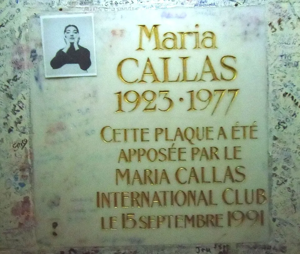 Üzerinde Maria Callas'ın gençlik yıllarından kalma küçük, siyah beyaz bir fotoğrafı, doğum (1923) ve ölüm (1977) tarihleri ile Maria Callas International Club tarafından 15 Eylül 1991'de yerleştirildiği bilgisi altın kabartma harflerle yazılı, etrafı karalamalarla dolu bir duvara sabitlenmiş parlak, açık renkli mermer bir anma plaketi görülüyor.